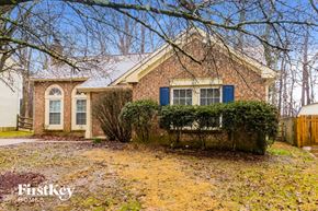 Charlotte house for rent - A brick house with a blue window and a sign that says "Firstkey Homes".