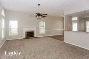 Charlotte house for rent - A spacious room with a fireplace and a ceiling fan.