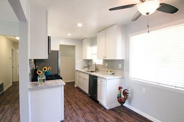 Sacramento house for rent - a kitchen with white cabinets and a large window
