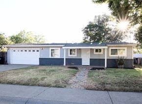 Sacramento house for rent - a blue and white house with a driveway and a garage door