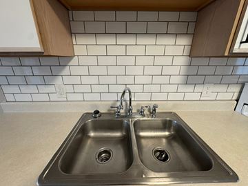 Rocky Mount apartment for rent - A kitchen with a double sink and a tile backsplash.