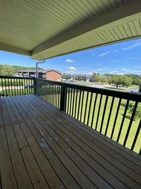 Rocky Mount apartment for rent - A wooden deck with a metal railing overlooks a grassy area.