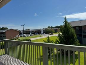 Rocky Mount apartment for rent - A view from a balcony overlooking a parking lot and buildings.