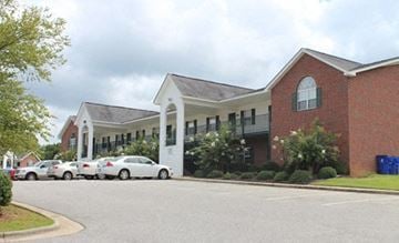 Nashville apartment for rent - A red brick building with a white entrance and cars parked in front.