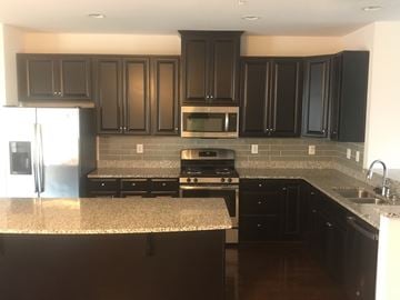 Capitol Heights house for rent - A kitchen with black cabinets and a granite countertop.