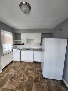 Cincinnati apartment for rent - A kitchen with white appliances and brown tiles.