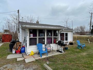 Lakeshore house for rent - A small white house with a porch and a blue chair.