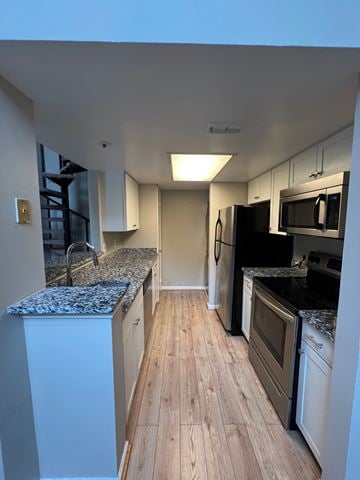 Laurel house for rent - A kitchen with white cabinets and a granite countertop.
