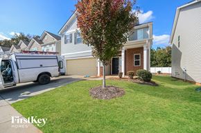 Charlotte house for rent - A tree with red leaves is in the front yard of a house with a white van parked in front.