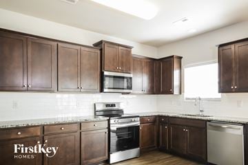 Charlotte house for rent - A kitchen with brown cabinets and a stove top oven.