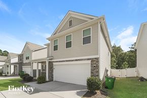Charlotte house for rent - a beige house with a white garage door and a green lawn