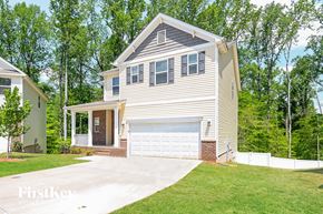 Charlotte house for rent - A two-story house with a garage is surrounded by trees.