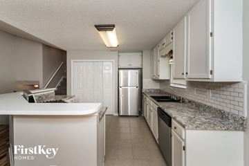 Douglasville house for rent - a kitchen with white cabinets and granite counter tops and a white refrigerator