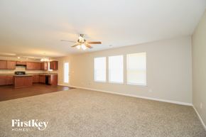 Winston Salem house for rent - an empty living room with a ceiling fan and a kitchen