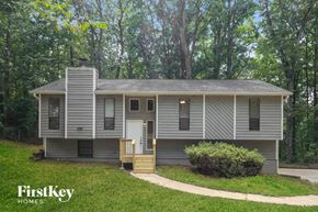 Douglasville house for rent - A house with a porch and a chimney is surrounded by trees.