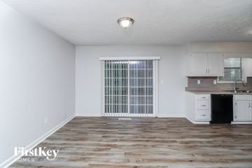 Douglasville house for rent - A spacious room with a window, wooden floor, and a kitchenette.