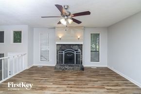 Douglasville house for rent - A living room with a fireplace and a ceiling fan.
