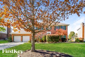 West Chester house for rent - A tree with orange leaves stands in front of a house with a sign that says "FirstKey Homes.".
