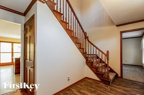 West Chester house for rent - A staircase with a wooden handrail and steps leading up to a landing with a white wall and a doorway.
