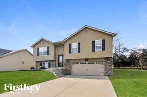 Wentzville house for rent - a beige house with a garage door and a lawn