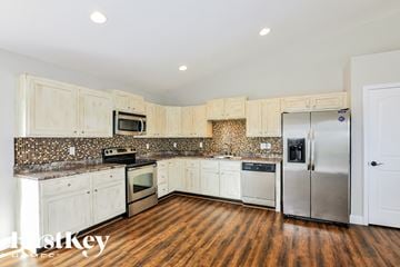 Wentzville house for rent - a kitchen with white cabinets and stainless steel appliances