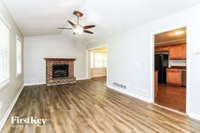 Kennesaw house for rent - A spacious living room with a fireplace and a ceiling fan.