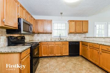 Marietta house for rent - a kitchen with wooden cabinets and black appliances