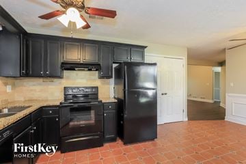 Powder Springs house for rent - A kitchen with black cabinets and a black fridge.