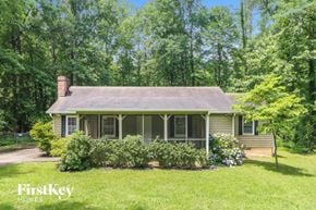 Marietta house for rent - A house with a porch surrounded by greenery.
