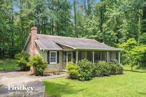 Marietta house for rent - A house with a porch and a chimney is surrounded by greenery.