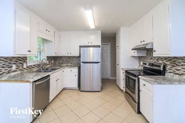 Marietta house for rent - A kitchen with white cabinets and a marble countertop.