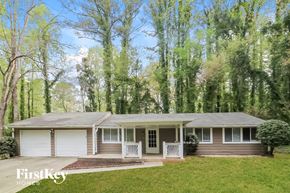 Marietta house for rent - A house with a porch and a garage is surrounded by trees.