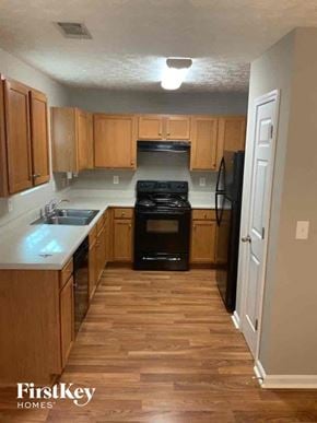 Dallas house for rent - an empty kitchen with wooden cabinets and a black stove
