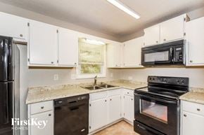 Dallas house for rent - a kitchen with white cabinets and black appliances