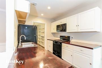 Duncanville house for rent - a kitchen with white cabinets and black appliances and a sink