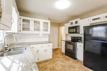 Dallas house for rent - a kitchen with black appliances and white cabinets