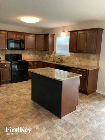 Woodstock house for rent - A kitchen with brown cabinets and a black stove top oven.