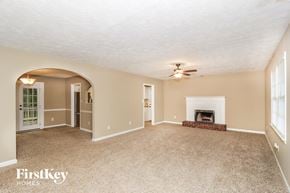 Kennesaw house for rent - an empty living room with a fireplace and a ceiling fan