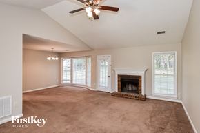 Powder Springs house for rent - A spacious living room with a fireplace and a ceiling fan.