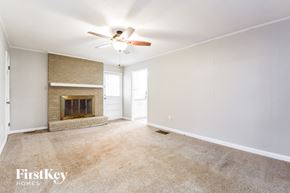 Dallas house for rent - an empty living room with a fireplace and a ceiling fan