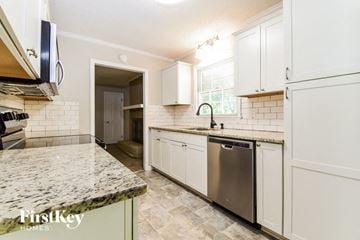 Dallas house for rent - a kitchen with white cabinets and a stainless steel dishwasher