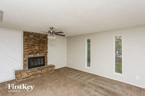 Flower Mound house for rent - A room with a stone fireplace and a ceiling fan.