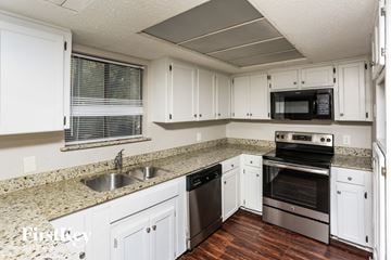 Flower Mound house for rent - A kitchen with white cabinets and a granite countertop.
