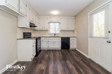 Hiram house for rent - a kitchen with white cabinets and black appliances and wood floors