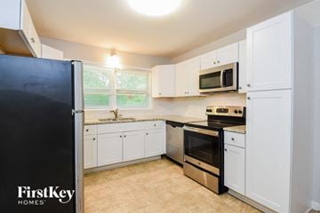 Marietta house for rent - a kitchen with white cabinets and a black refrigerator