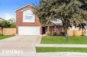 New Braunfels house for rent - A red brick house with a white garage door and a tree in front.