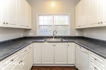 High Point house for rent - a kitchen with white cabinets and a sink and a window