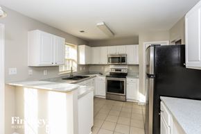 Charlotte house for rent - a kitchen with white cabinets and a black refrigerator