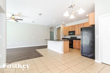 Kissimmee house for rent - A kitchen with a black refrigerator and wooden cabinets.