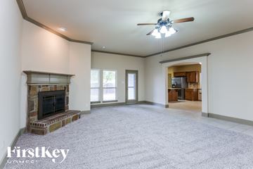 Burleson house for rent - A spacious living room with a fireplace and a ceiling fan.